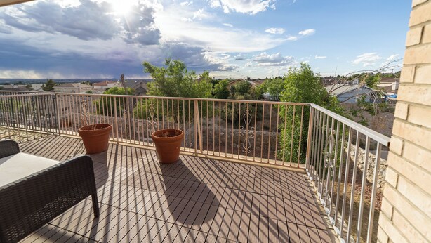 A balcony with a metal railing, a table, and two potted plants. - Modern Smart Townhouse | Premium Amenities | Nearby Restaurants | Full Kitchen (El Paso)