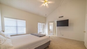 A bedroom with a bed, a ceiling fan, a TV mounted on the wall, and a door leading to another room. - Modern Smart Townhouse | Premium Amenities | Nearby Restaurants | Full Kitchen (El Paso)