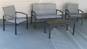 En terrasse med tre stole og et bord.