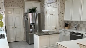 A kitchen with white cabinets, a stainless steel refrigerator, and a tiled floor. - Unwind and Relax 4 Bedroom Stay (Humble)