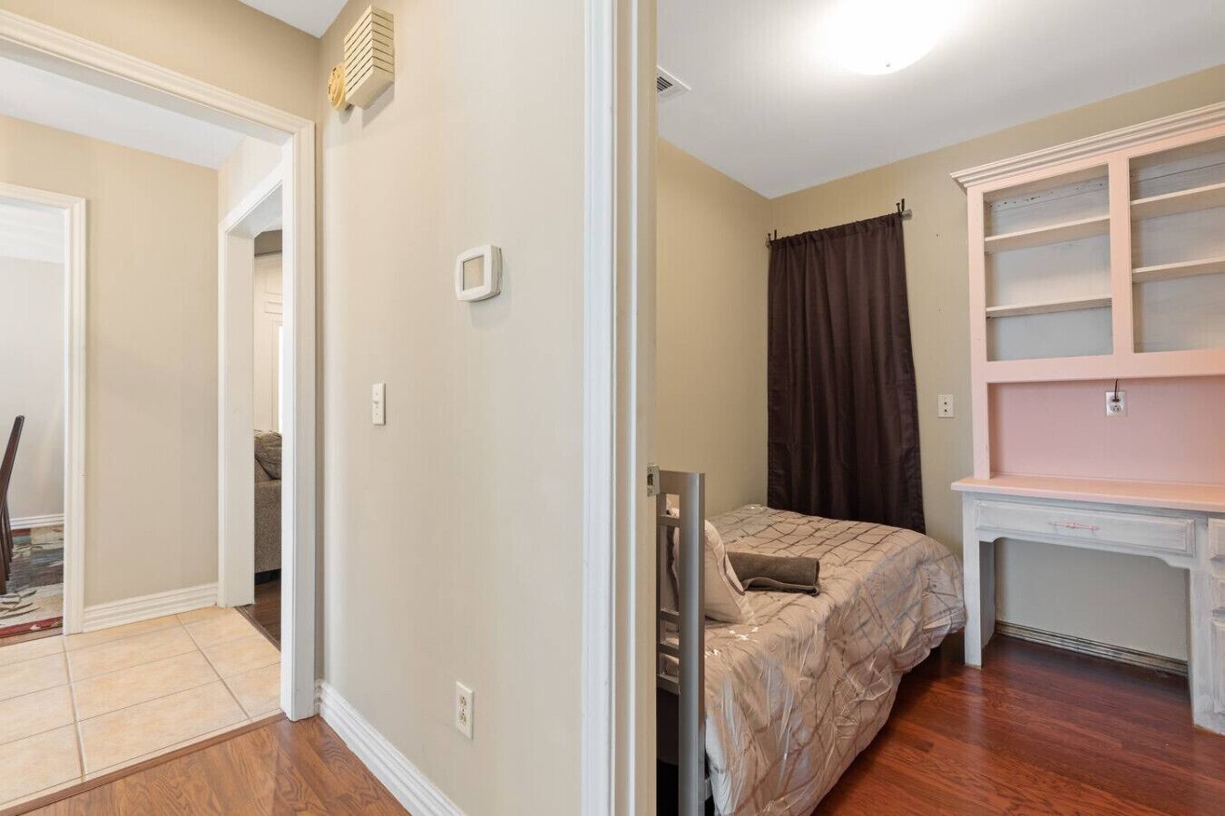 Une chambre à coucher comprenant un lit, un bureau avec une chaise, une armoire et une porte donnant sur une autre pièce.