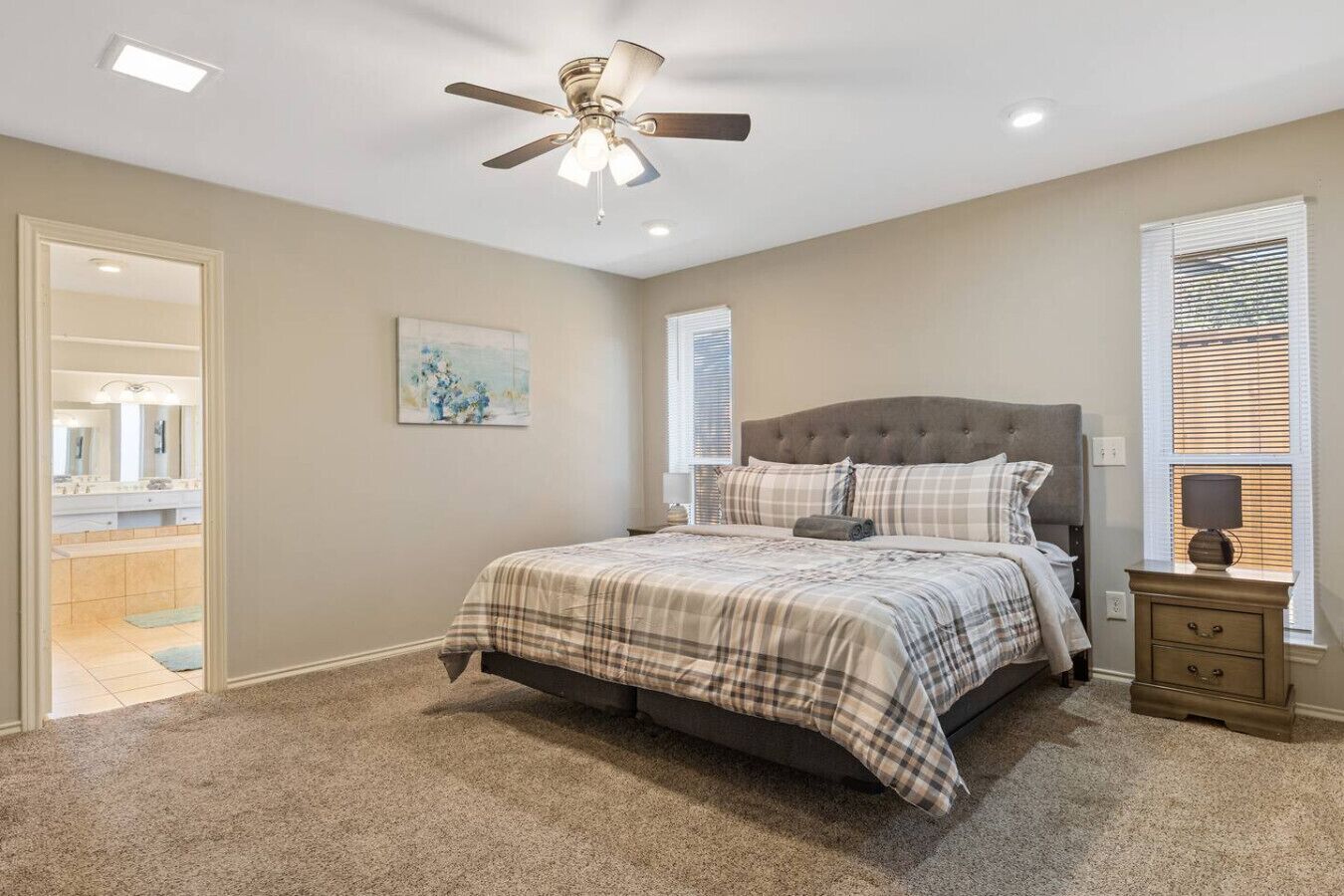 A bedroom with a bed, a nightstand, a ceiling fan, and a window with blinds.