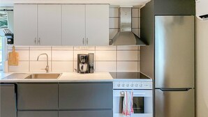 Una cocina moderna con armarios blancos, electrodomésticos de acero inoxidable y un salpicadero de azulejos.