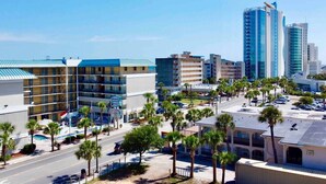 A hotel with multiple floors, a parking lot, and palm trees.