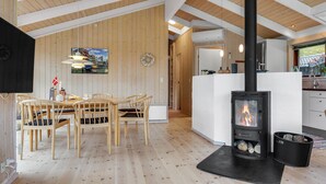 Un interior acogedor con una zona de comedor de madera, una chimenea central y una cocina con una estufa moderna.
