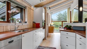 Una cocina moderna con armarios de madera, un lavavajillas Bosch y un amplio ventanal con vistas al verdor.