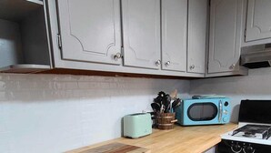 A kitchen with grey cabinets, a wooden countertop, a microwave, a toaster, and a stove.