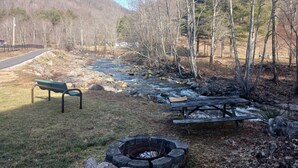 A park with a picnic table, a bench, and a fire pit.