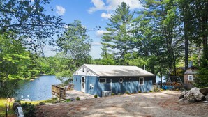 Une cabane avec un quai s’avançant dans un lac, entourée d’arbres.