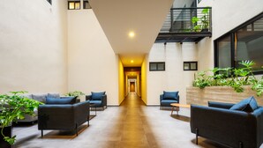 A modern indoor space with a central corridor, seating areas with sofas, and potted plants. - Capitalia Downtown Del Valle (Mexico City)