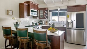 Een moderne keuken met houten kastjes, een roestvrijstalen koelkast en een centraal eiland met barstoelen.