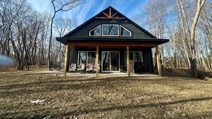 A modern house with a large porch, large windows, and a sloped roof.