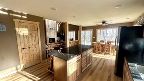 A spacious kitchen with wooden cabinetry, a central island, and a dining area with wooden chairs and a table.