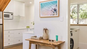 Una cocina moderna con armarios blancos, una mesa de madera, un microondas y una lavadora.