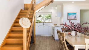 Una cocina moderna con armarios blancos, una escalera de madera y un comedor con una mesa y sillas.