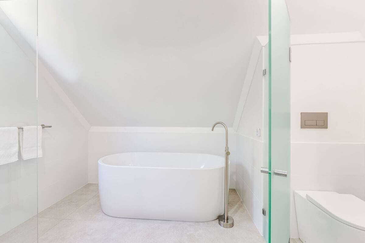 A modern bathroom with a freestanding bathtub, a glass shower enclosure, and a toilet.