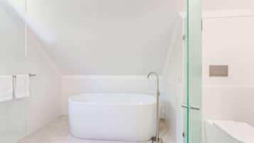 A modern bathroom with a freestanding bathtub, a glass shower enclosure, and a toilet.