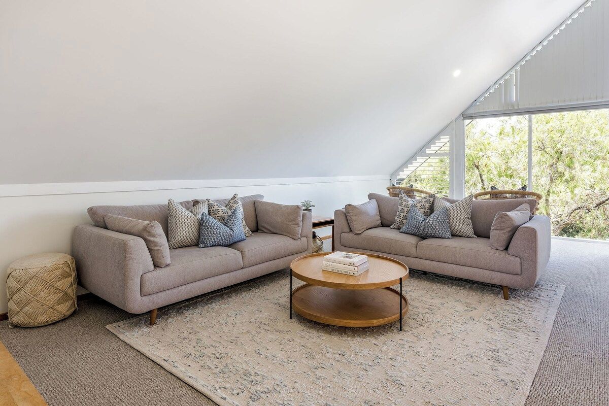 A modern living room with a sofa set, a coffee table, and a patterned rug.