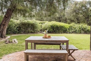 A wooden picnic table with benches in a garden setting.