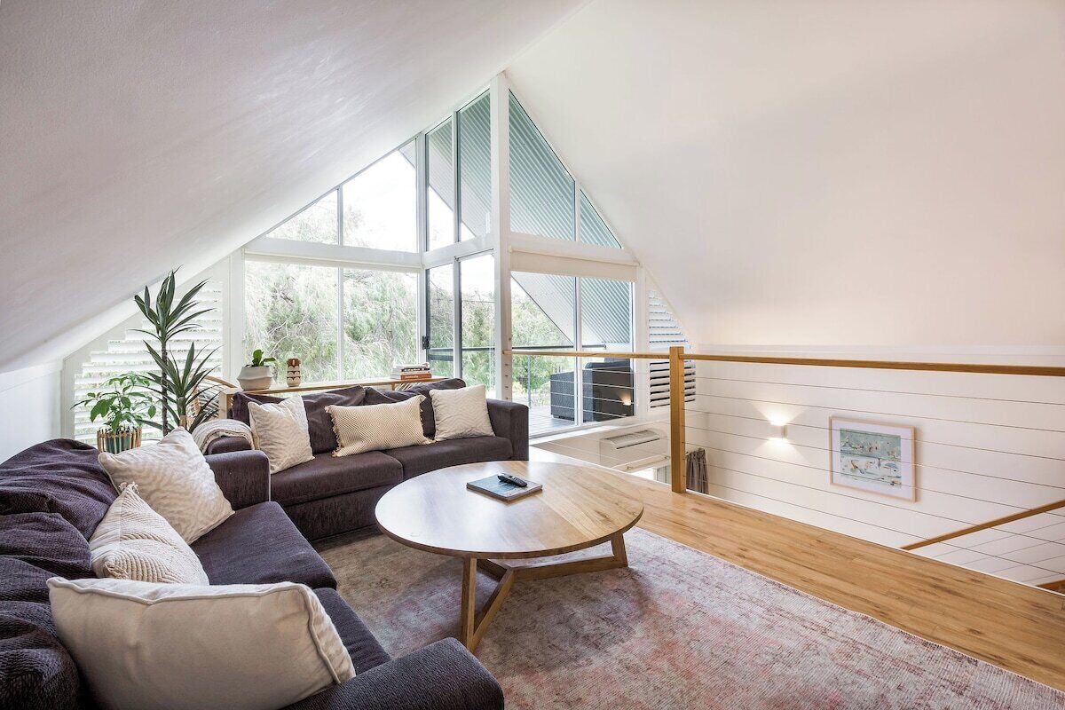 Sink into the spacious upstairs lounge beneath soaring vaulted ceilings, where comfortable seating, natural light and a Smart TV create an inviting place to unwind together.
