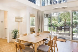 A spacious room with a large dining table, comfortable seating, a potted plant, and a view of the outdoors.