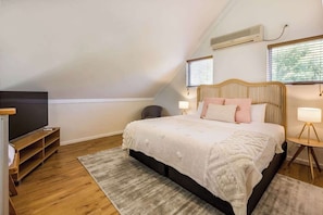 Une chambre avec un lit, une télévision, une fenêtre et un appareil de climatisation.