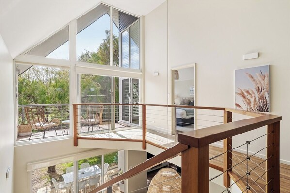 A modern interior with a staircase, large windows, and outdoor seating.