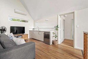 A modern kitchen with white cabinets, a stainless steel dishwasher, and a small island with a sink.