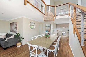 Un intérieur moderne comprenant un coin repas, un canapé, un escalier et une cuisine.