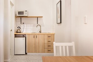 A compact kitchen with a microwave, kettle, and small refrigerator.