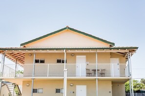 A two-story building with a balcony on the upper floor, a door on the lower floor, and a small window on the upper floor.