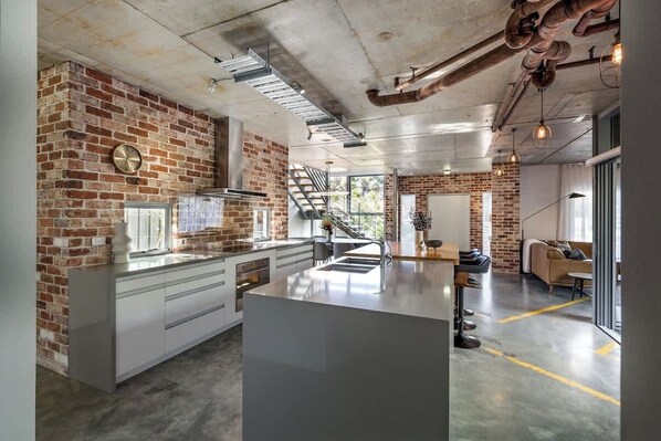 A modern kitchen with a brick wall, stainless steel appliances, and a central island.