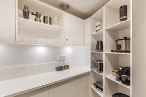 Een keuken met witte kastjes, een koffieapparaat, een broodrooster en diverse keukengerei.