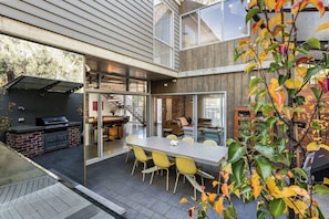 Une maison moderne dotée d’un patio, d’un coin repas et d’un barbecue.