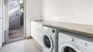 Een wasruimte met een wasmachine, een droger en een wasbak.