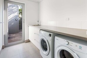 A laundry area with a washing machine, a dryer, and a sink.