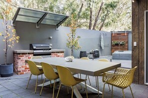Une terrasse extérieure équipée d’un barbecue, d’une table à manger et de chaises.