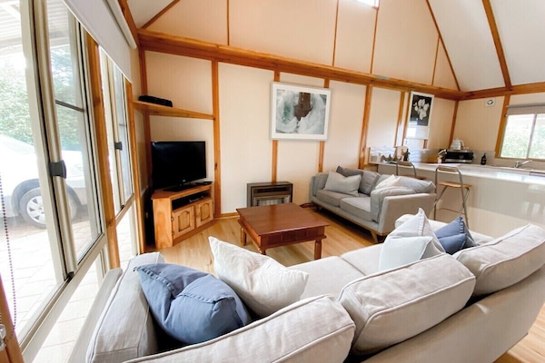The soaring timber-lined ceilings and open-plan layout create a warm, airy space for relaxing together after a day by the beach.