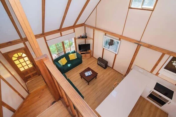 Una habitación con estructura de madera, un sofá, un televisor y una chimenea.