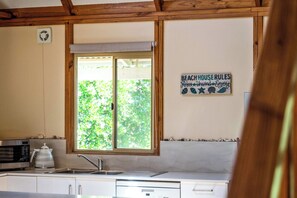 Eine Küche mit Fenster, Spüle, Mikrowelle und Kaffeemaschine.