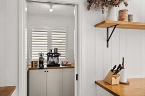 A kitchen with white cabinets, a coffee machine, and a wooden countertop.