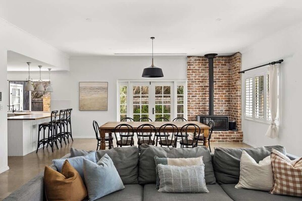 A modern living space with a dining area, a fireplace, and a kitchen visible in the background.