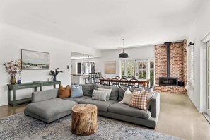 Ein modernes Wohnzimmer mit einem Ecksofa, einem runden Holztisch und einem Kamin.