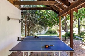 Una mesa de ping pong montada en un espacio exterior con una pérgola encima.