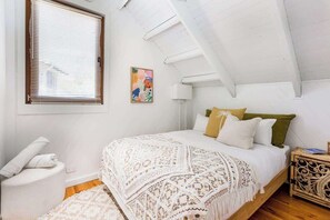 A bedroom with a bed, a window with blinds, a bedside table, and a wall-mounted lamp. - Mika Cabin—Breezy Family Haven, Easy Walk to Beach (Eagle Bay)