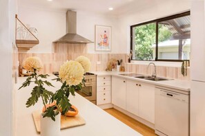 A modern kitchen with white cabinetry, a stainless steel sink, and a window with a view of greenery.
