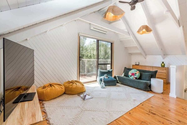 A spacious loft with a large window, a ceiling fan, a sofa, and a coffee table.