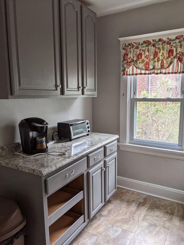 Enjoy cooking in this kitchen with a granite countertop, coffee maker, and toaster, surrounded by classic cabinetry and a view of the outdoors.