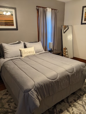 Relax in a cozy retreat with a large bed, bedside table, and mirror.
