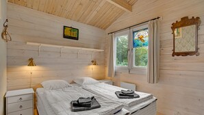 A cozy bedroom with two beds, a nightstand, a wall-mounted lamp, a window with curtains, and a mirror. - Awesome home in Kalundborg with WiFi (Kalundborg)